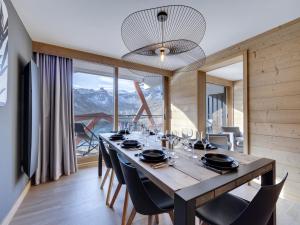 ein Esszimmer mit einem Tisch mit Stühlen und einem großen Fenster in der Unterkunft Appartement moderne 7 pers. avec babyfoot, buanderie et vue sur le lac - FR-1-641-2 in Tignes