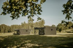 a building in the middle of a grass field at Laimeskalni in Koknese