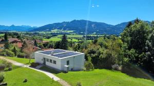 a white house with solar panels on a green field at Naturgenuss in Oy-Mittelberg