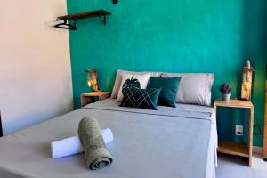 Un dormitorio con una cama con una pared verde. en Estúdios Sol e Mar, aconchego e charme em Tucuns, en Búzios