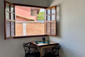 una mesa pequeña con 2 sillas frente a una ventana en Estúdios Sol e Mar, aconchego e charme em Tucuns, en Búzios