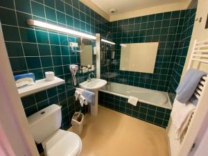 a green tiled bathroom with a toilet and a sink at Hôtel restaurant de la fontaine in Villiers-sur-Suize