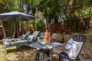 uma mesa e cadeiras e um guarda-sol num quintal em Keiskama B & B em Port Elizabeth