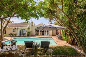 uma piscina com cadeiras e um guarda-sol ao lado de uma casa em Keiskama B & B em Port Elizabeth