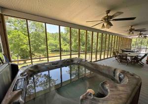 une grande véranda grillagée avec un canapé et un ventilateur de plafond dans l'établissement Brushy Creek Lodge - Riverfront, Hot Tub, Fire Pit, à Mentone