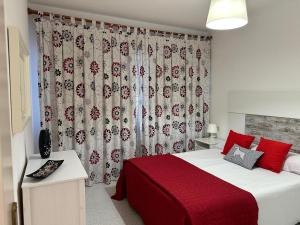 a bedroom with a bed with red pillows and a curtain at Casa Cabana in El Médano