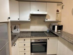 a kitchen with white cabinets and a stove top oven at Casa Cabana in El Médano +7 photos