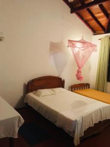 une chambre avec deux lits et un cerf-volant rose accroché au mur dans l'établissement Bentota Lotus Resort and Villa Bentota, à Hettiwatta