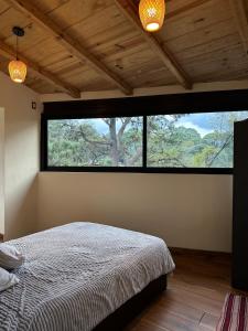 ein Schlafzimmer mit einem Bett und einem großen Fenster in der Unterkunft Luz de Altura in Valle de Bravo