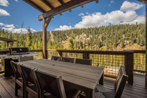 a wooden table and chairs on a deck with a view at Spanish Peaks - Highlands Cabin 59 in Big Sky