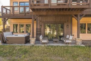 a deck with a hot tub and chairs on a house at Spanish Peaks - Highlands Cabin 59 in Big Sky