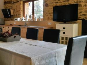 una cocina con una mesa con sillas y un televisor en Chez Rambaud, en Chadaleix