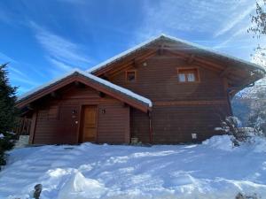 une cabane en rondins avec de la neige devant elle dans l'établissement Chalet chaleureux avec jacuzzi et cheminée à Méribel - FR-1-688-64, à Méribel