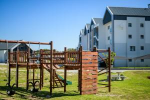 a wooden playground in a park next to a building at Costa Bella in Gqeberha