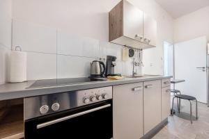 a kitchen with white cabinets and a stove top oven at Altenbeken- Ferienwohnung 1 in Altenbeken