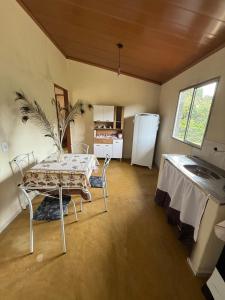 Zimmer mit einem Tisch und einer Küche mit einem Kühlschrank. in der Unterkunft Recanto Zechini in Vargem Alta