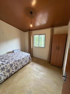 ein leeres Schlafzimmer mit einem Bett und einem Fenster in der Unterkunft Recanto Zechini in Vargem Alta