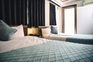 een hotelkamer met twee bedden en een raam bij The Kabuki-do Inn Haneda in Tokyo
