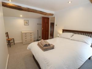 - une chambre avec un lit blanc et une serviette dans l'établissement 11 Hollin Well Cottage, à Sowerby Bridge
