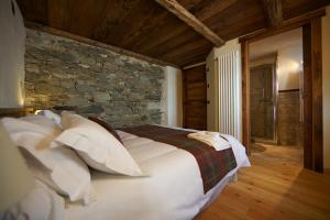 een slaapkamer met een groot bed en een stenen muur bij A barma drola in Brusson