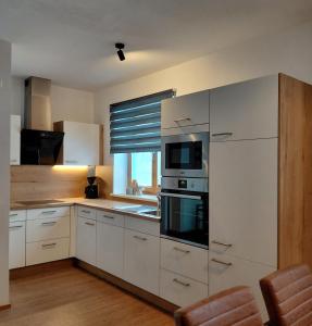 a kitchen with white cabinets and a microwave and a window at Kumming incl Nationalparkcard in Rauris