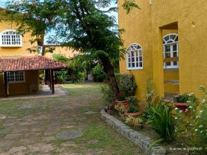 a yellow building with a tree in the yard at Pousada Fonte da Samaritana in Vila Velha