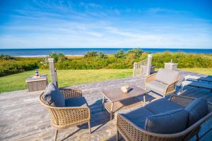 eine Terrasse mit Stühlen, einem Tisch und Meerblick in der Unterkunft Ocean Dream Beach House in Saint Peters