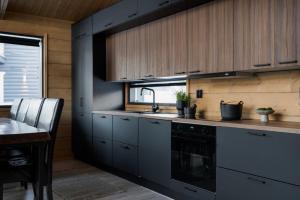 - une cuisine avec des placards gris, un évier et une table dans l'établissement Saana's chalets Levi, à Levi
