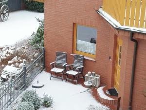 a snow covered balcony of a house with two chairs at Ferienwohnung Heike Heitmann - Maisonette-Wohnung oder Apartment in Eystrup