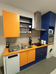 een keuken met blauwe en oranje kasten en een wastafel bij Le nid in Colmar