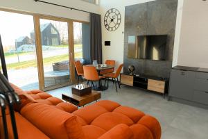 a living room with an orange couch and a table at Górskie Kąty Resort Michałkowa in Michałkowa