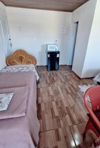 ein Zimmer mit zwei Betten und Holzboden in der Unterkunft KITNET S4 em TORRES-RS - Confortável com cama casal box, cama de solteiro bicama, televisão, geladeira, micro-ondas, chaleira elétrica, ar-condicionado split - Anfitriã Superhost no BnB in Torres