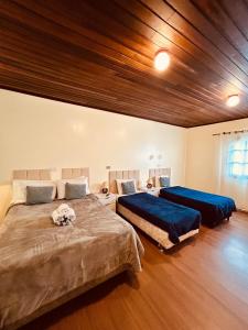 a bedroom with two beds and a wooden ceiling at Pousada Valle do Sol in Campos do Jordão