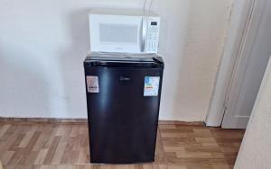 eine Mikrowelle auf einem Kühlschrank in der Unterkunft KITNET S4 em TORRES-RS - Confortável com cama casal box, cama de solteiro bicama, televisão, geladeira, micro-ondas, chaleira elétrica, ar-condicionado split - Anfitriã Superhost no BnB in Torres