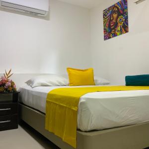 two beds with yellow and white sheets in a room at Hotel ITACO in Cartagena de Indias