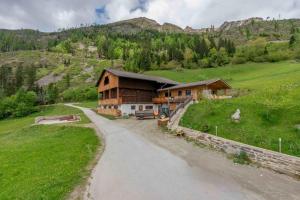 a house on a hill with a road in front at Ferienwohnungen Niederarnigerhof Familie Bauernfeind in Kals am Großglockner