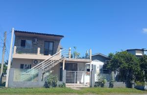 ein Haus mit einer Treppe davor in der Unterkunft KITNET S4 em TORRES-RS - Confortável com cama casal box, cama de solteiro bicama, televisão, geladeira, micro-ondas, chaleira elétrica, ar-condicionado split - Anfitriã Superhost no BnB in Torres + 17 Fotos