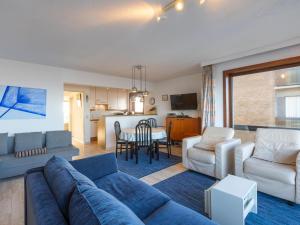 a living room with a blue couch and a kitchen at Dunekant - 0203 + park.6 in Miami Wijk