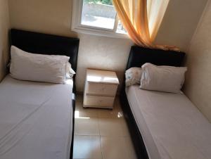 two beds in a small room with a window at maison soleil in Ifrane