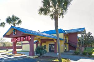 a building with a palm tree in front of it at OYO Hotel Pensacola I-10 & Hwy 29 in Pensacola