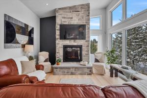 un salon avec un canapé et une cheminée dans l'établissement Modern Waterfront Cottage on the Rouge River & Spa, à Rivière-Rouge