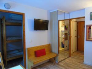 Cette chambre comprend un banc, une télévision et un miroir. dans l'établissement Studio cosy 4 pers, proche télécabine & commerces - FR-1-561-42, à Valfréjus