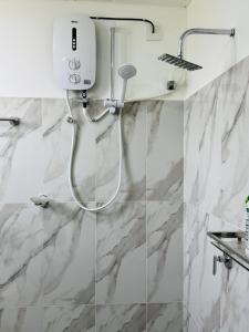 une douche blanche dans une salle de bains aux murs en marbre dans l'établissement Freedom Peak Cabin Ambewela, à Nuwara Eliya