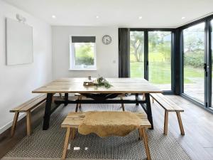 une salle à manger avec une table et des bancs en bois dans l'établissement Hen Stablau, à Llanfihangel-Glyn-Myfyr