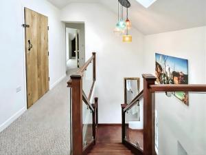 un couloir avec un escalier doté d'une rampe en bois et d'une porte dans l'établissement Hen Stablau, à Llanfihangel-Glyn-Myfyr