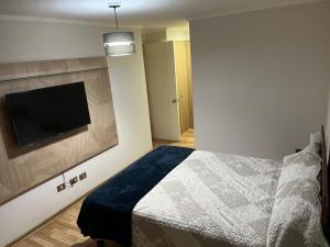 Un dormitorio con una cama y un televisor de pantalla plana. en Departamentos Innova, en Copiapó