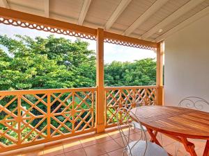 a balcony with a wooden table and a large window at Charmante Villa "Coquelicot" à Orient Baie, Proche Plage et Commerces, Confort et Détente Garantis - FR-1-734-10 in Orient Bay