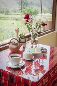 einen Tisch mit einer Tasse Kaffee und einer Vase Blumen in der Unterkunft Hotel Casa Suite Inka in Ollantaytambo + 75 Fotos