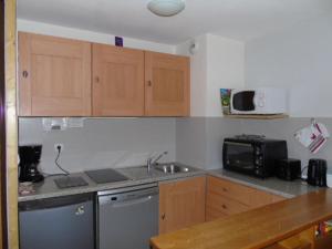 a kitchen with wooden cabinets and a sink and a microwave at Charmant 2P + Coin Nuit, 300m des Commerces et Ski, 6 Pers, Draps Inclus - FR-1-561-93 in Valfréjus +3 photos