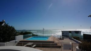 a swimming pool with the ocean in the background at Seaside apartment - Big Bay beach in Cape Town